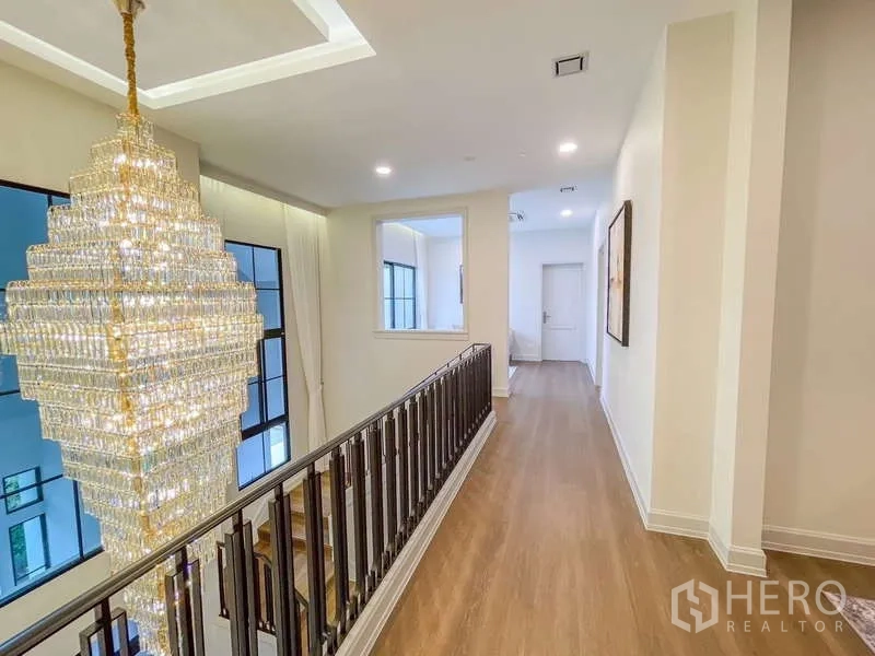 Detached House for rent in Saphan Sung, Bangkok - Upper hallway with a statement crystal chandelier and wood flooring.