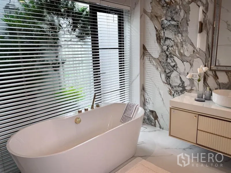 Detached House for rent or sale - Bathroom with a freestanding tub by the window and a marble feature wall.