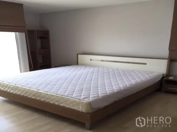 公寓 出租在Watthana, Bangkok - 宽敞主卧，配双人床与木质家具，自然采光充足。