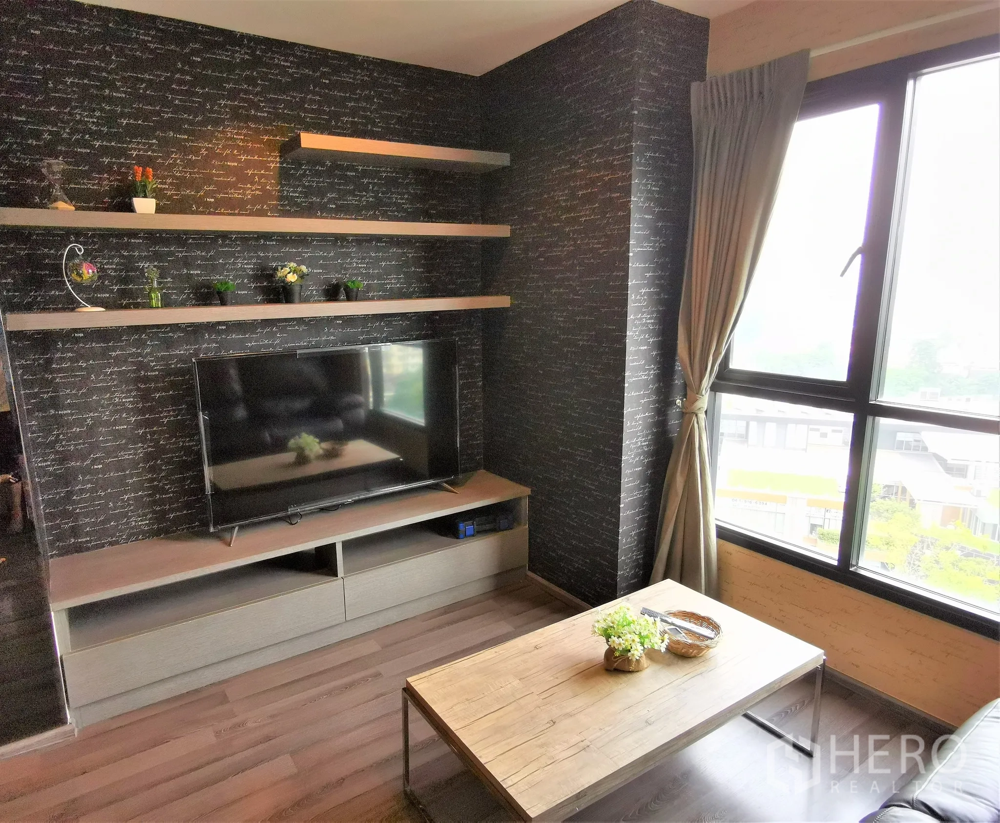 Condominium for rent or sale in Watthana, Bangkok - Entertainment wall with floating shelves and flat-screen TV next to curtained window and coffee table.