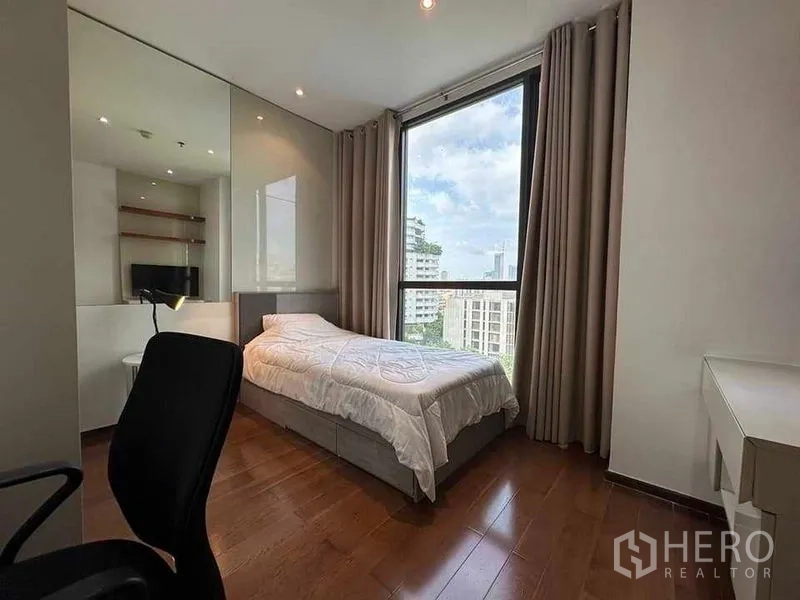 公寓 出租在Khlong Toei, Bangkok - 次卧配单人床与书桌，大窗与镜面衣柜，城市景观。