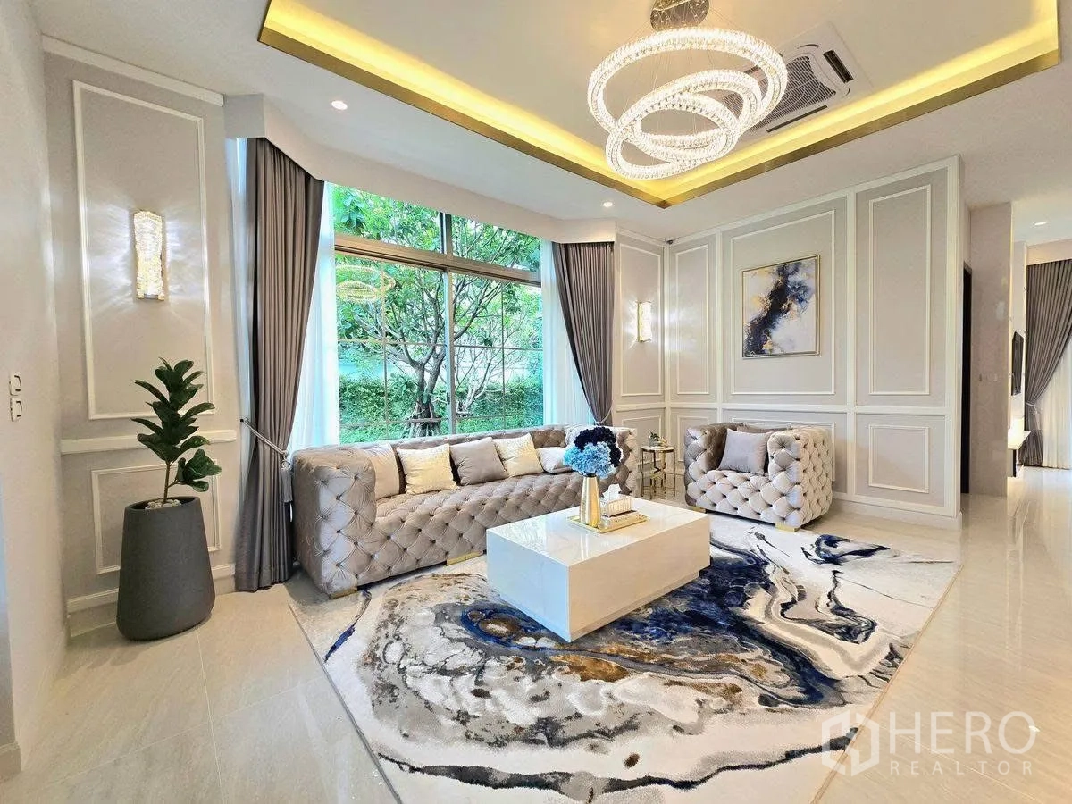 บ้านเดี่ยว for rent or sale in Bang Phli, Samut Prakan - มุมห้องนั่งเล่นพร้อมบัวผนัง หน้าต่างพาโนรามาเห็นสวน และโคมระย้าคริสตัล