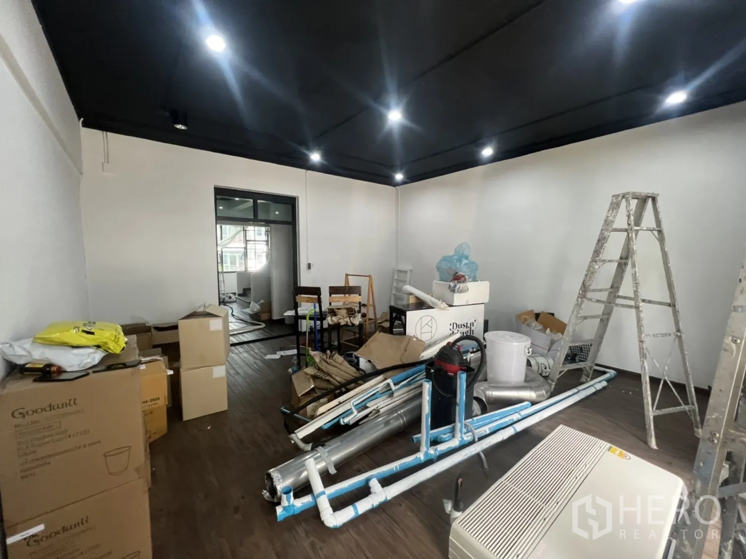 Retail Space for rent in Watthana, Bangkok - Workroom filled with renovation tools, ladders, piping and boxes on dark wood flooring.