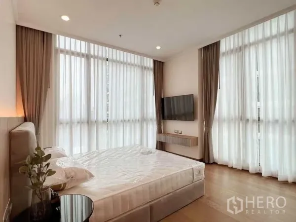 คอนโด ให้เช่าในWatthana, Bangkok - ห้องนอนมุมอาคาร หน้าต่างสูงรอบด้าน ผ้าม่านโปร่ง ทีวีติดผนัง และพื้นไม้