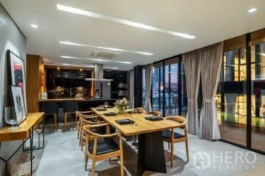 带办公室的家 出售在Khlong Toei, Bangkok - 餐厅与开放式厨房，长木桌临推拉玻璃门。