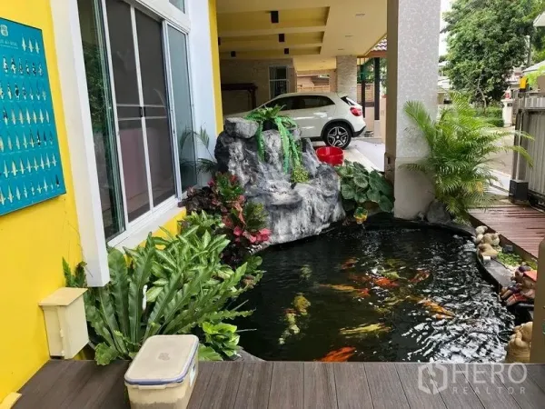 Detached House for sale in Wang Thonglang, Bangkok - Front garden water feature with a rock waterfall and decorative pond beside the covered driveway.