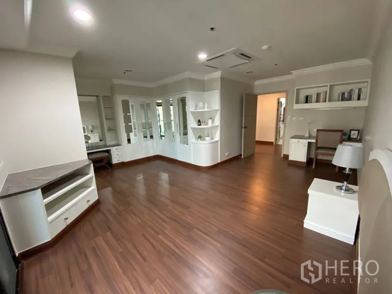 Condominium for rent in Watthana, Bangkok - Spacious master bedroom featuring wardrobes, built-in shelving, and polished wood flooring.