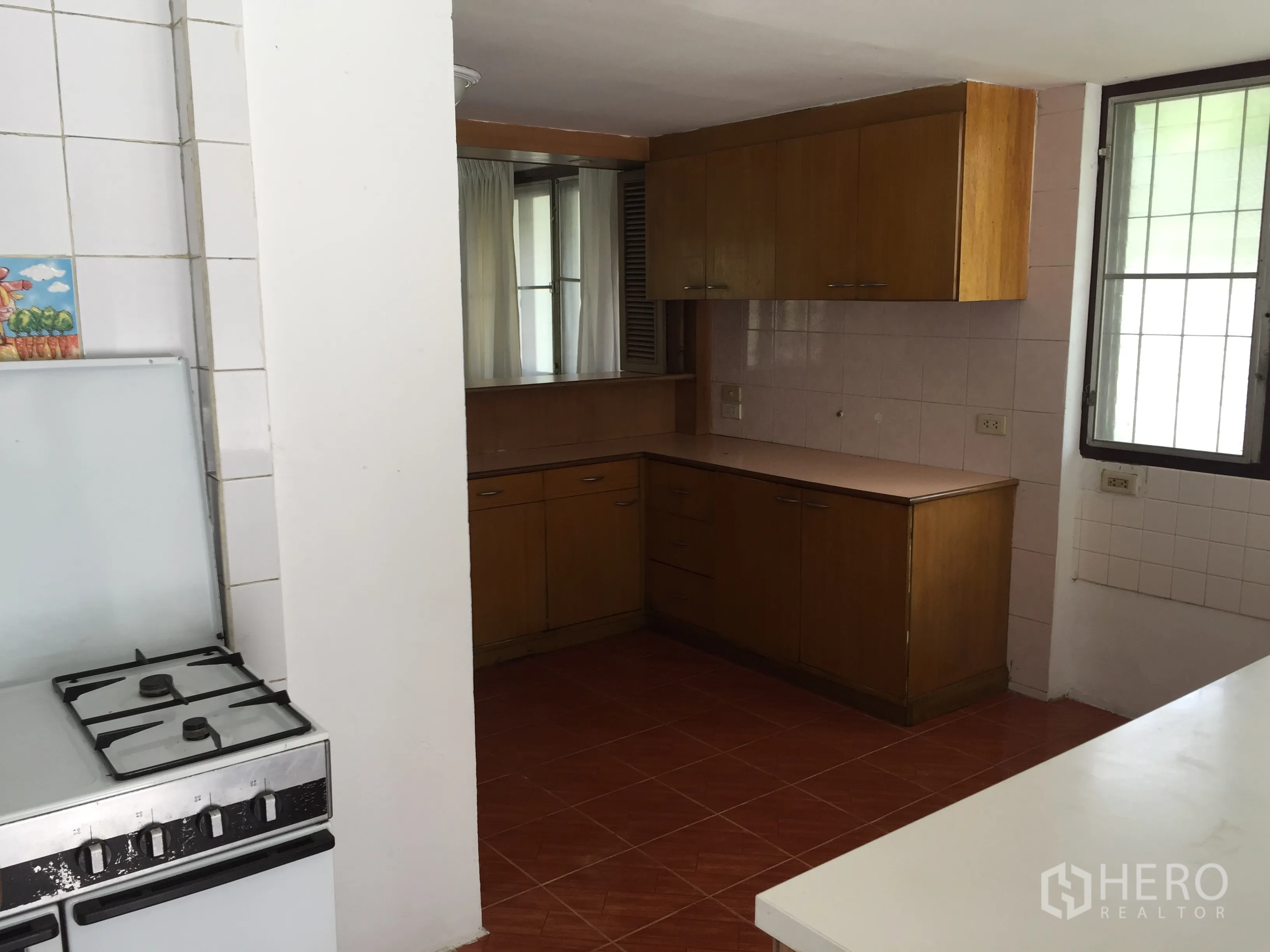 Townhouse for rent in Yan Nawa, Bangkok - Functional kitchen with gas stove, tiled walls and wooden cabinets.