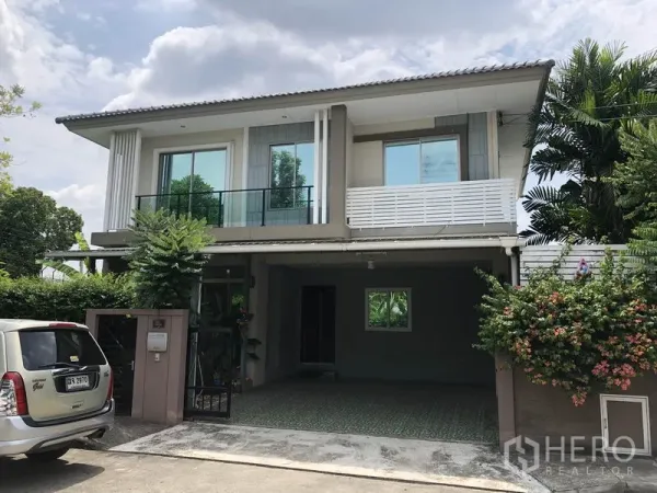 Detached House for rent in Suan Luang, Bangkok - Two-storey detached house facade with balcony, gated driveway and lush trees.