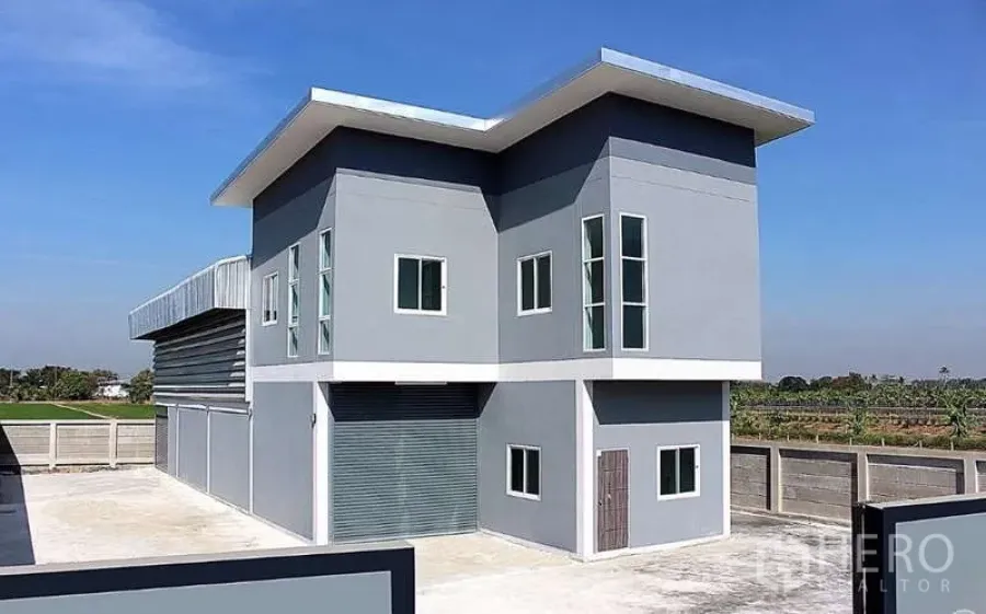 货栈 出售在Pathum Thani - 建筑外观：两层办公室连体仓库，卷闸门与宽阔硬化院场。
