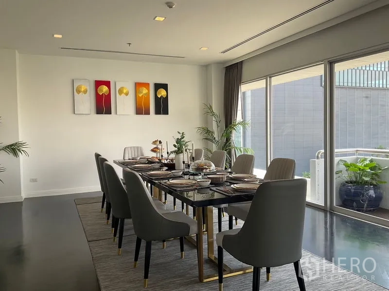 Apartment for rent in Sathon, Bangkok - Elegant dining room with long table, upholstered chairs and floor‑to‑ceiling windows.