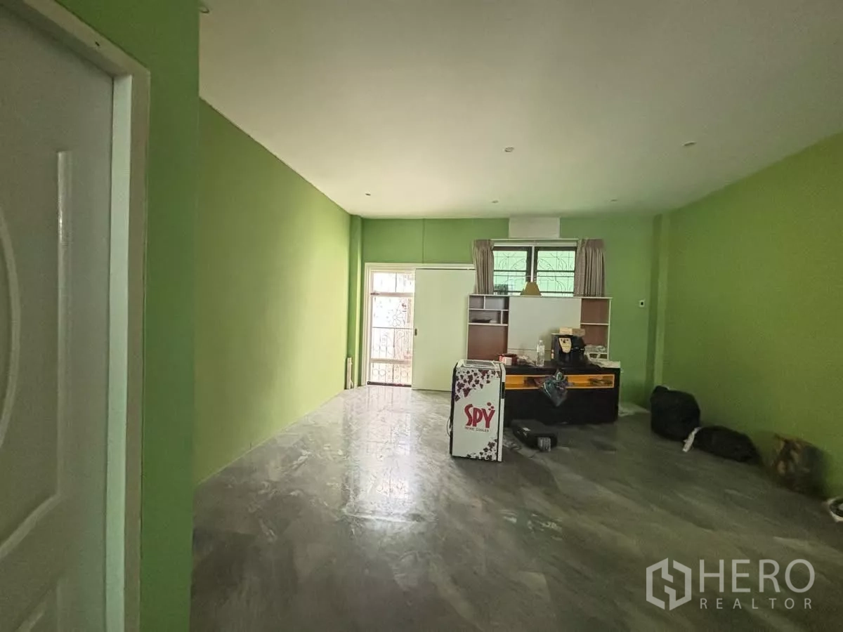 Shophouse for rent in Watthana, Bangkok - Open-plan ground floor with green walls, polished flooring and a rear window.