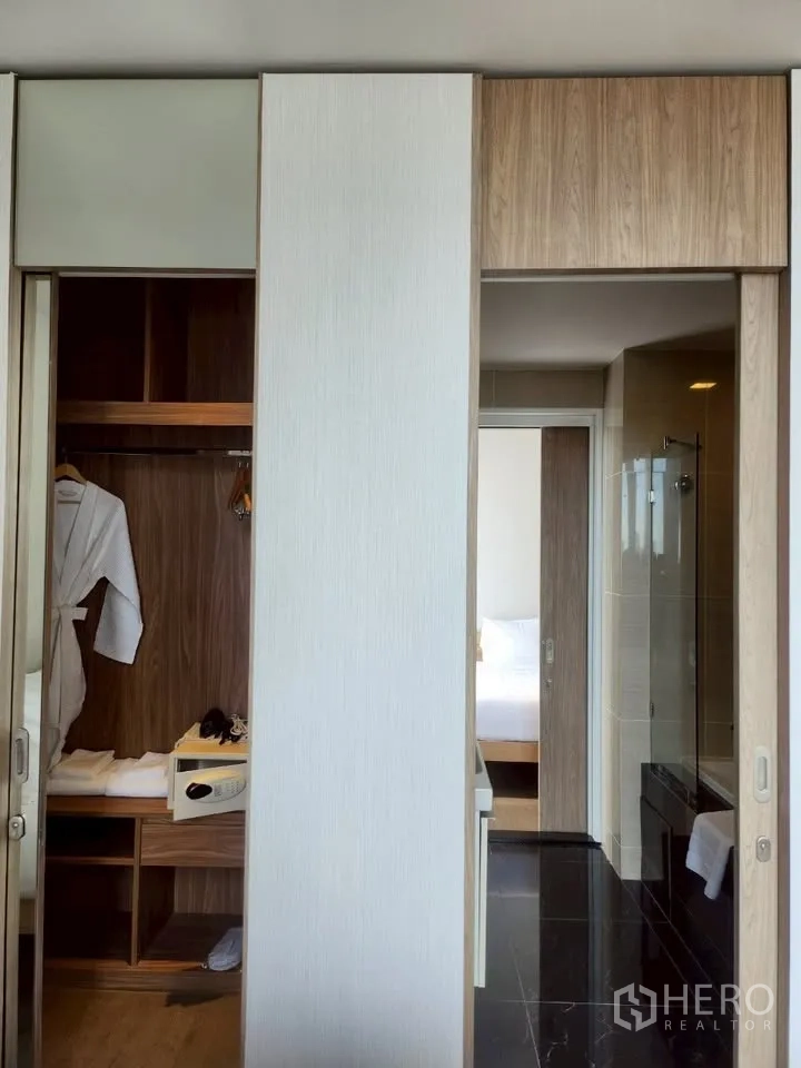 Condominium for rent in Khlong Toei, Bangkok - Sliding‑door wardrobe with built‑in safe and access to a bathroom with glass shower enclosure.
