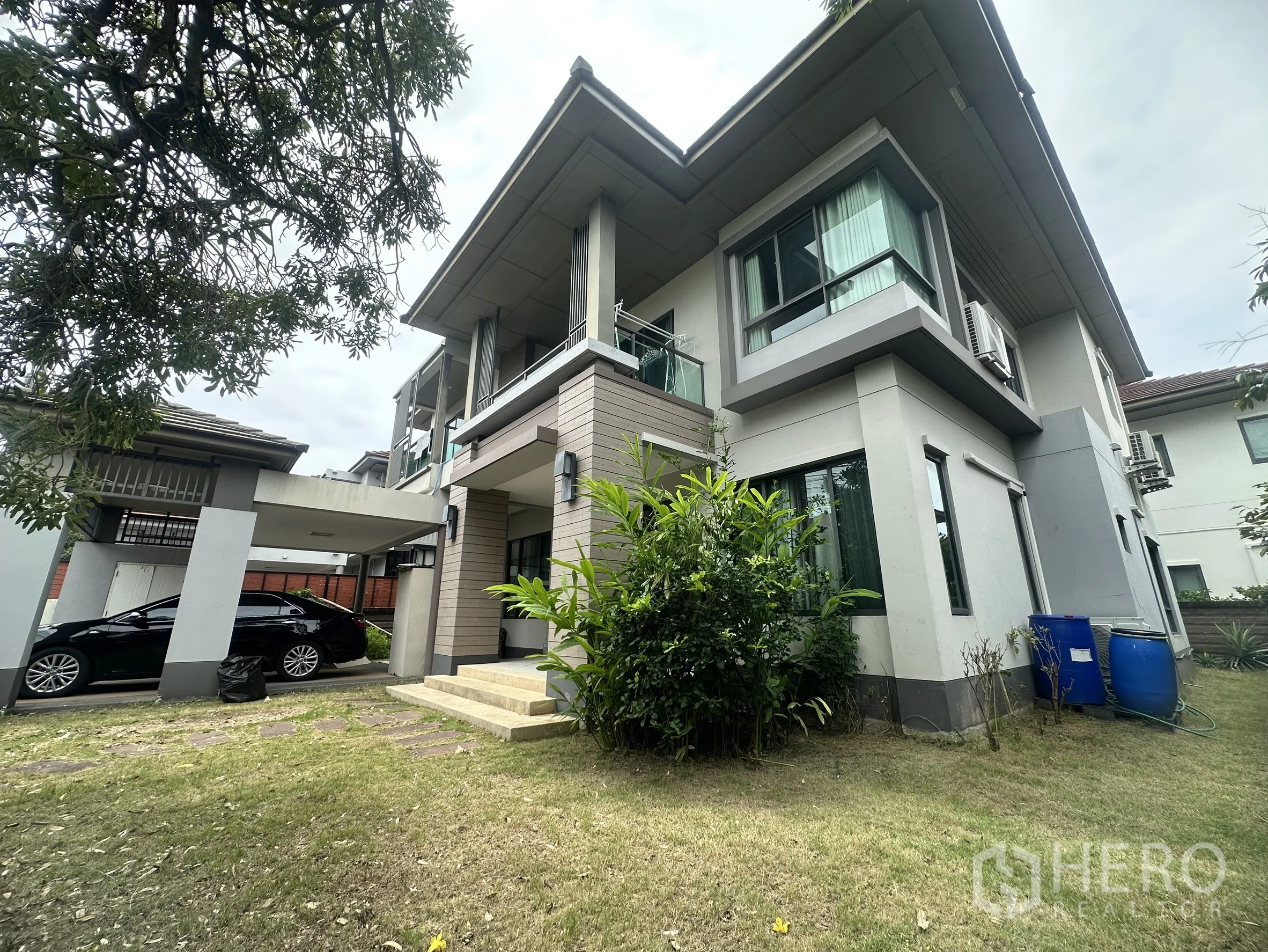 独栋房屋 for sale in Pak Kret, Nonthaburi - 房屋侧面，带有车棚、草坪花园和现代外立面。