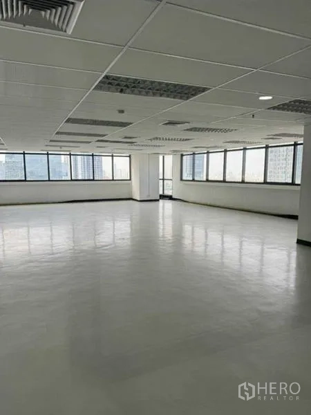 办公空间 出租或出售在Phaya Thai, Bangkok - 转角办公区配大幅窗景与城市视野，白色地面与嵌入式照明。