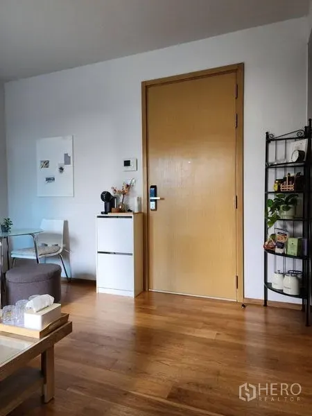 Condominium for rent in Watthana, Bangkok - Entrance zone with wooden door, compact cabinet and open shelving on warm wood flooring.