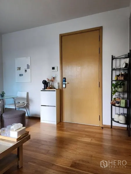 Condominium for rent in Watthana, Bangkok - Entrance zone with wooden door, compact cabinet and open shelving on warm wood flooring.