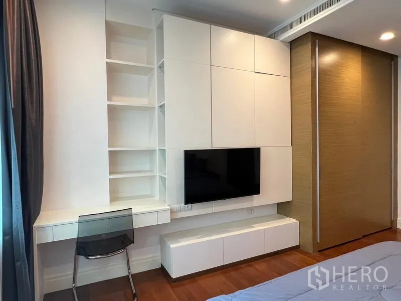 Condominium for rent in Khlong Toei, Bangkok - Bedroom with built-in desk, shelving and sliding wardrobe door.