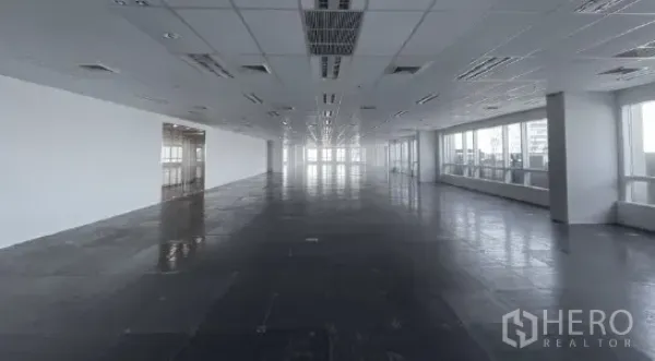 Office Space for rent - Long column-free office floor plate with suspended ceiling, AC vents, and windows on both sides.
