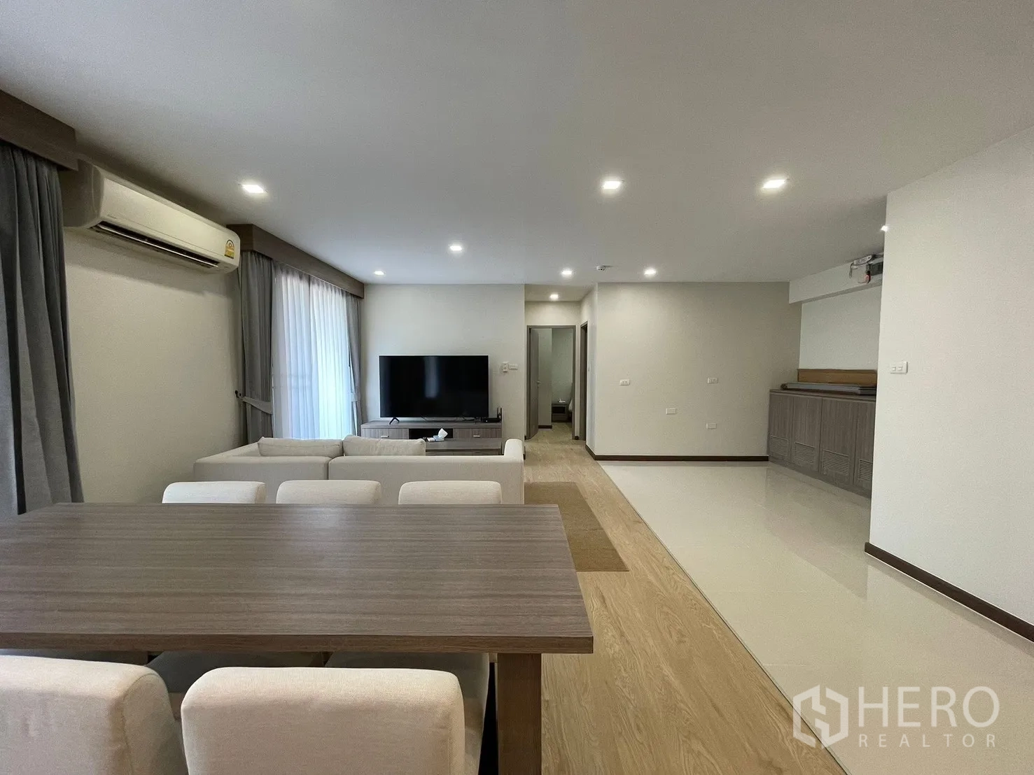 คอนโด for rent in Watthana, Bangkok - ห้องนั่งเล่นกว้างพร้อมโซฟาเข้ามุม โต๊ะทานข้าวยาว และทีวีจอใหญ่ในพื้นที่โอเพ่นแปลนสว่าง