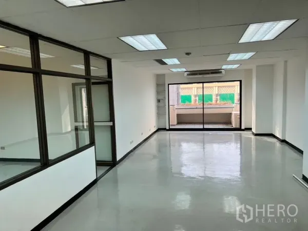 Office Space for rent in Pathum Wan, Bangkok - Bright open-plan office with polished floors, fluorescent lighting, wall air-conditioning and sliding glass doors to a balcony.