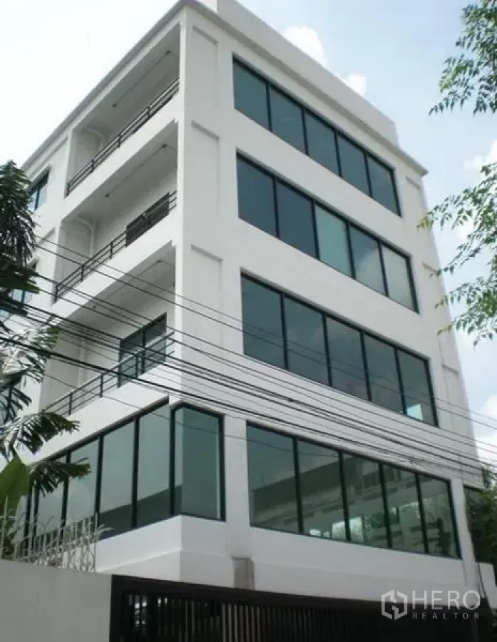 带办公室的家 出租或出售在Wang Thonglang, Bangkok - 现代白色多层办公楼，大片落地窗与阳台。