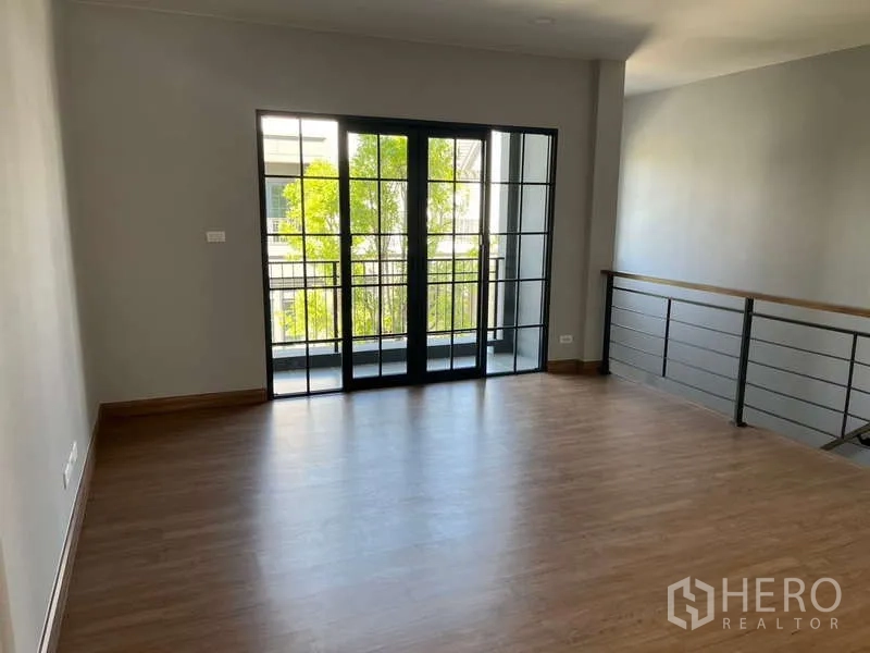 Detached House for rent in Bang Phli, Samut Prakan - Upper-floor family area with wood flooring and sliding glass doors opening to a balcony.