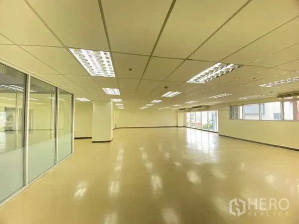 办公空间 出租在Watthana, Bangkok - 明亮工作区，长窗墙、结构柱与荧光灯照明。