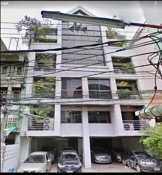 办公空间 出售在Ratchathewi, Bangkok - 中高层办公楼外立面，玻璃幕墙、绿意阳台与一层有顶停车位。