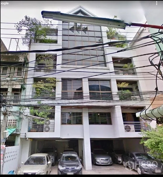 办公空间 出售在Ratchathewi, Bangkok - 中高层办公楼外立面，玻璃幕墙、绿意阳台与一层有顶停车位。