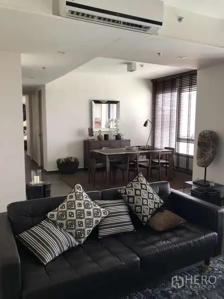公寓 出售在Watthana, Bangkok - 时尚客厅，黑色皮沙发、餐桌椅与高窗百叶。