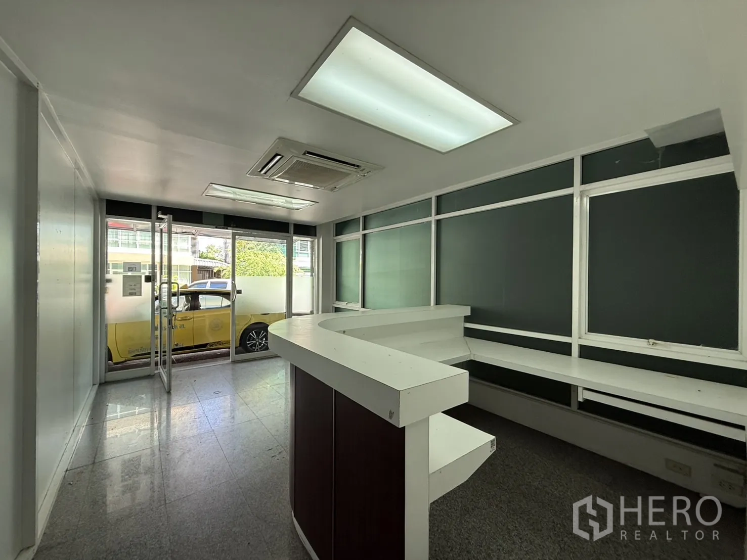 办公空间 出租在Bueng Kum, Bangkok - 接待区朝向玻璃入口，带内置工作台与吊顶空调