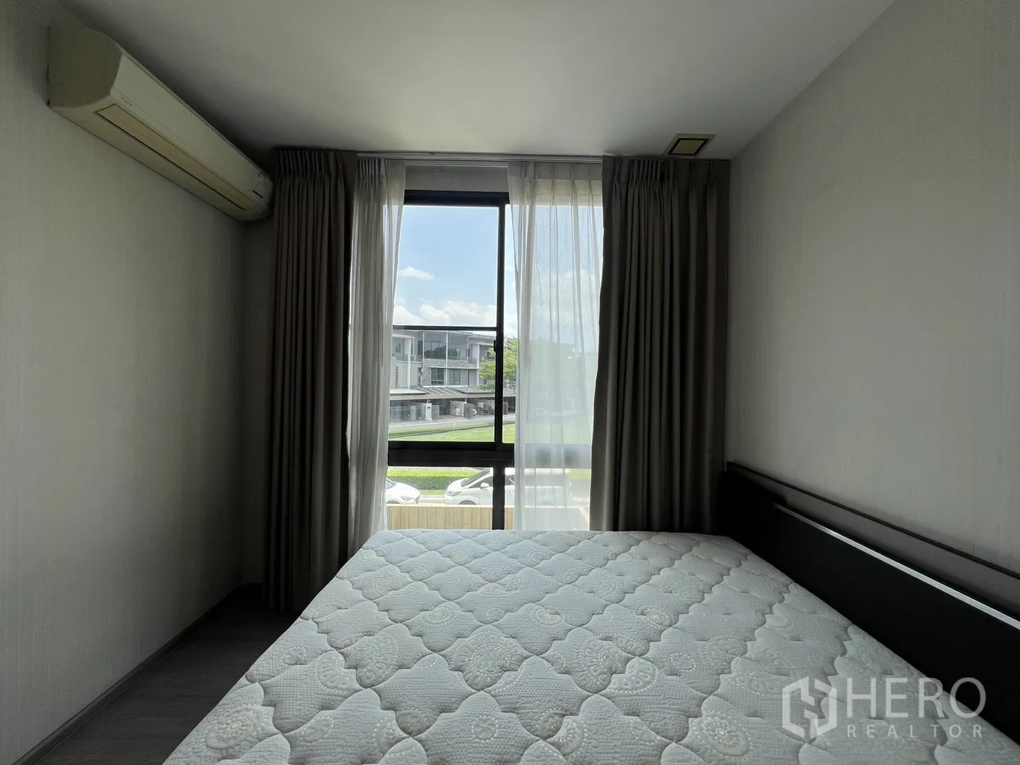 Townhouse for rent in Lat Phrao, Bangkok - Secondary bedroom with double bed, curtains, air conditioner and street-facing window.