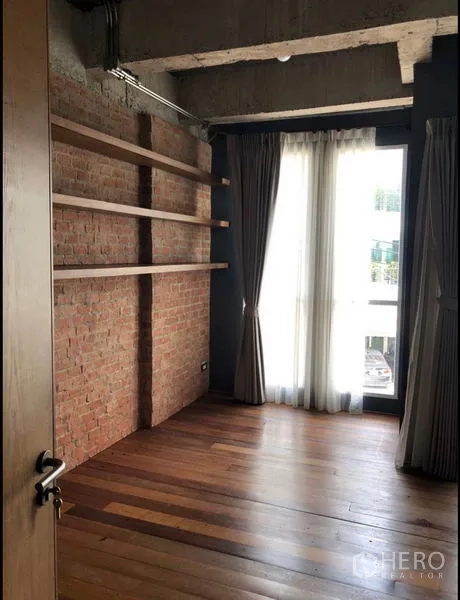 ทาวน์เฮาส์ ขายในWang Thonglang, Bangkok - ห้องนอนผนังอิฐโชว์แนว ชั้นไม้ลอย และประตูกระจกเปิดสู่ระเบียง