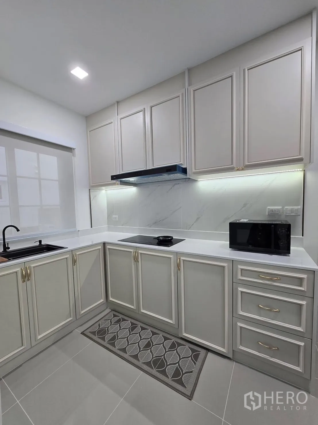 Semi-detached House for rent in Mueang Samut Prakan, Samut Prakan - U-shaped kitchen showing induction hob, under-cabinet lighting and classic paneled cabinetry.