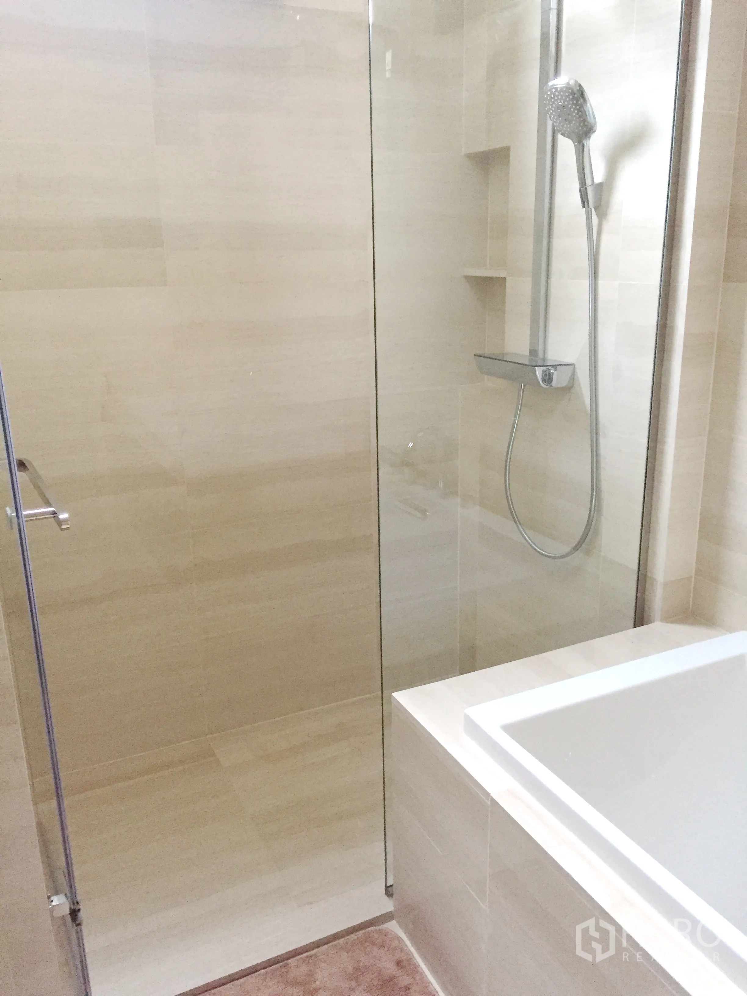 Condominium for rent in Watthana, Bangkok - Walk-in glass shower with rain showerhead and built-in shelves next to a bathtub.