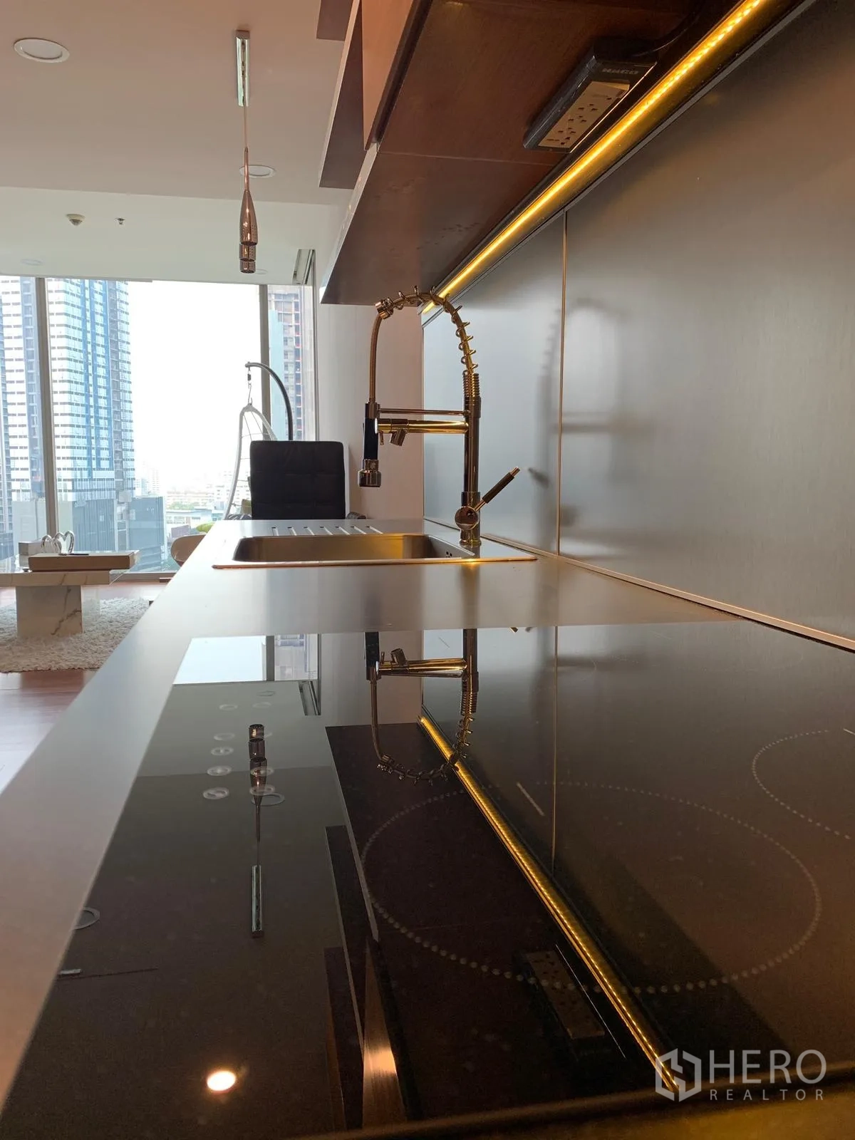 Condominium for sale in Khlong Toei, Bangkok - Sleek countertop with induction hob and pull‑down faucet overlooking a city view.