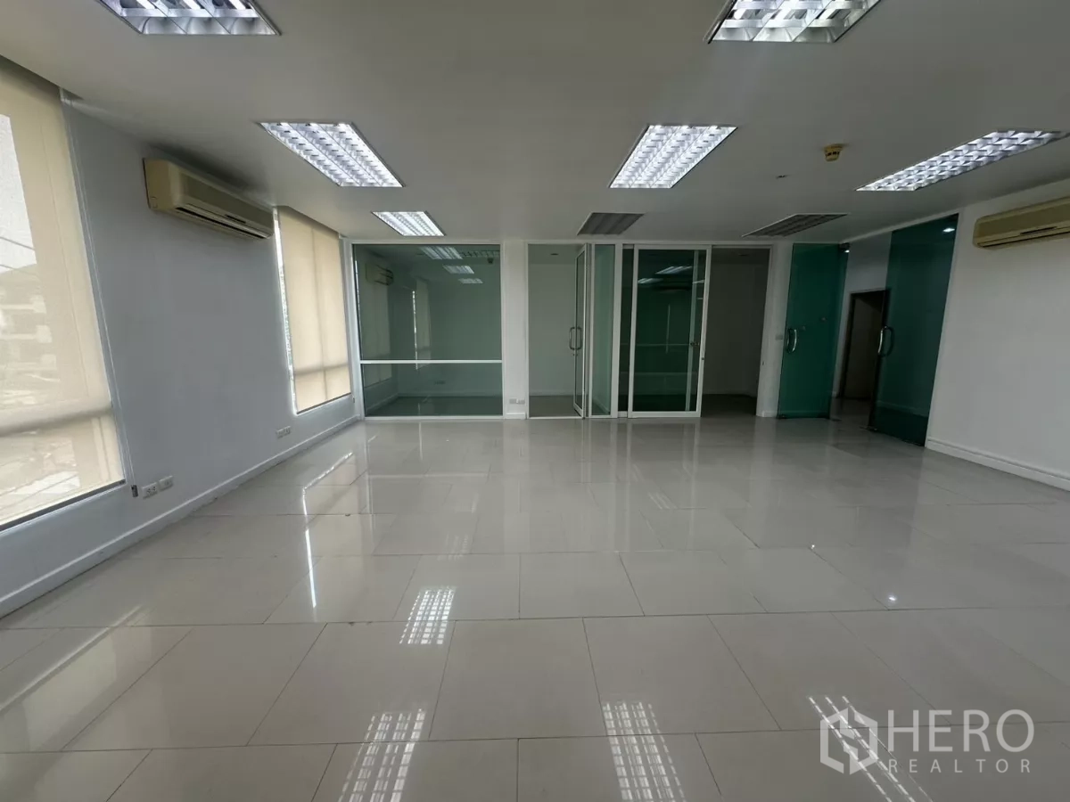 Office Space for rent in Huai Khwang, Bangkok - Open-plan space showing sliding glass doors to enclosed rooms and glossy tile flooring.