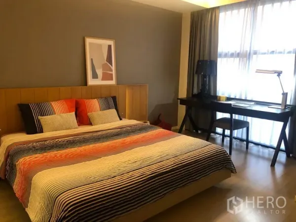 公寓 出租在Watthana, Bangkok - 明亮卧室，木质床头的特大床，窗边书桌与轻薄窗帘