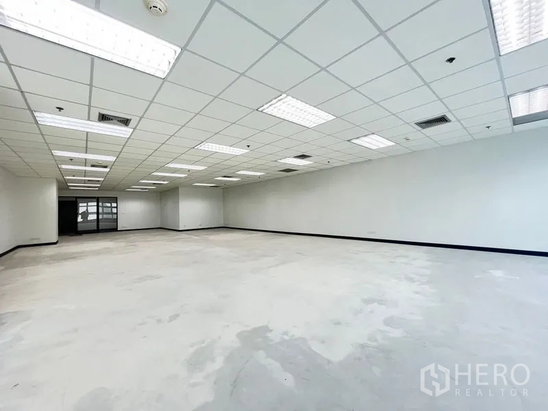 Office Space for rent in Khlong Toei, Bangkok - Spacious open-plan office with grid ceiling, LED lighting, AC vents, white walls and a rear glass entry.
