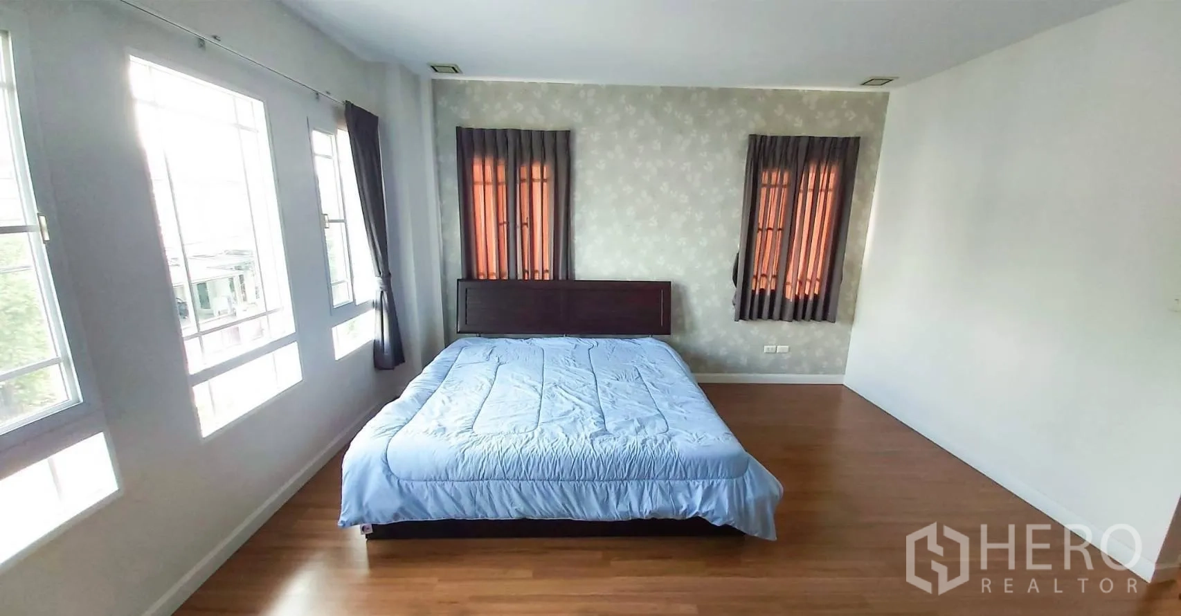 Detached House for sale in Bang Kapi, Bangkok - Spacious master bedroom with multiple windows, wood flooring and a bed.