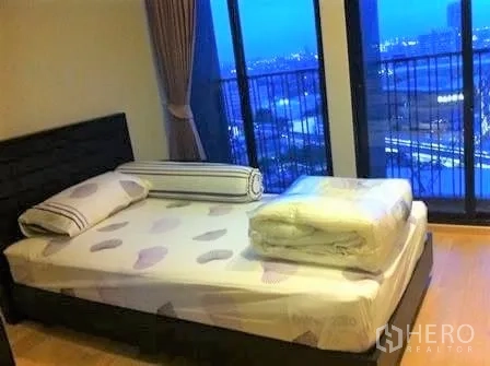 Condominium for rent in Watthana, Bangkok - Second bedroom with bed set against full‑height windows and sweeping night skyline outlook.