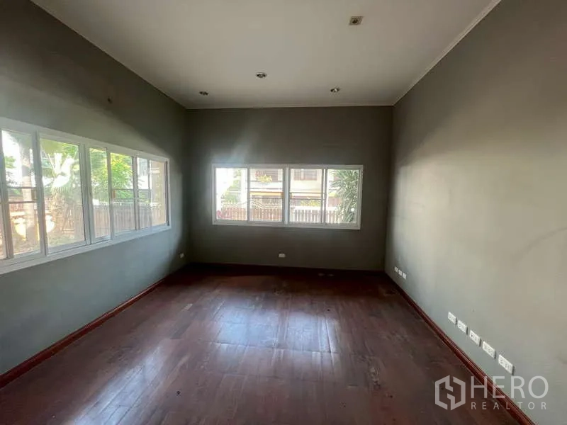 Detached House for rent in Watthana, Bangkok - Bright room with long strip windows overlooking greenery and wood floors.