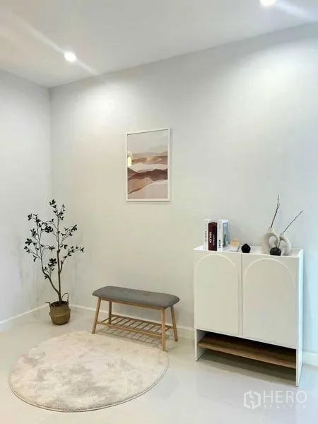 Townhouse for sale in Khlong Toei, Bangkok - Cozy corner with bench, round rug, slim cabinet and indoor plant against a white wall.