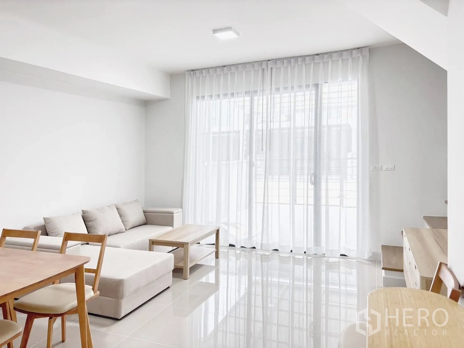 Townhouse for rent in Bang Phli, Samut Prakan - Living room opening to large sliding glass doors with sheer curtains for natural light.