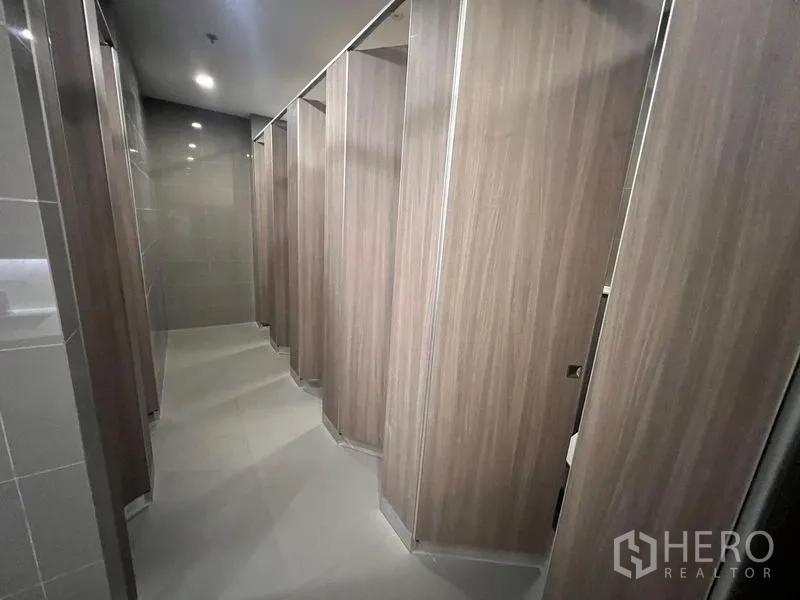 Office Space for rent - Row of restroom stalls with wood-look partitions and tiled floors.