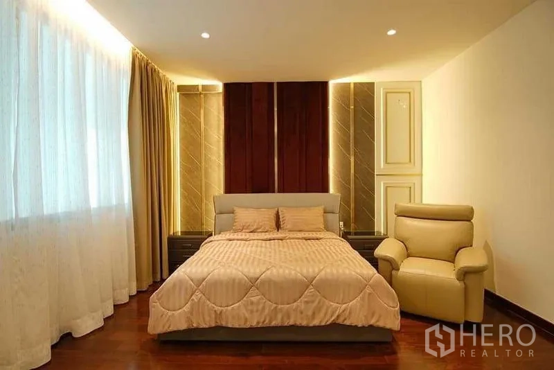 独立式住宅 出售在Lat Krabang, Bangkok - 温暖灯光的主卧，特色背景墙与木地板。