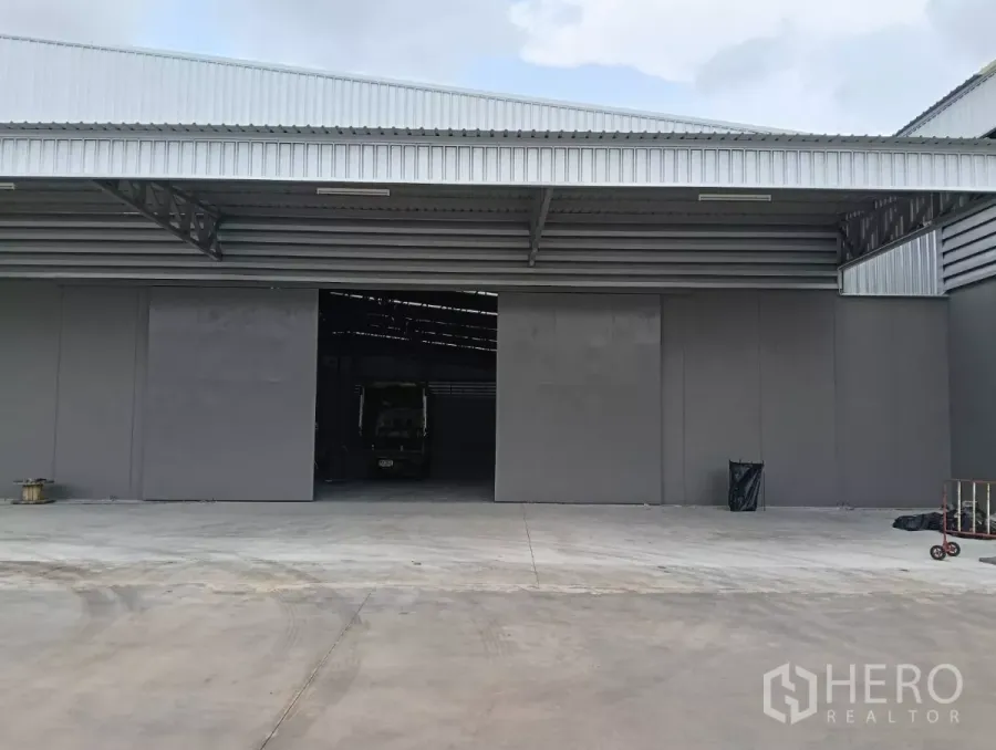 货栈 出租在Samut Prakan - 装卸区卷门开启，宽阔的卸货平台，仓库内有卡车。