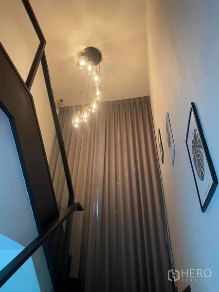 Detached House for rent in Lat Krabang, Bangkok - Staircase with sleek black railing, pendant chandelier and floor-to-ceiling curtains.