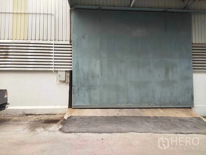 Warehouse for rent in Mueang Samut Sakhon, Samut Sakhon - Close-up of loading dock ramp with oversized metal sliding door under canopy.
